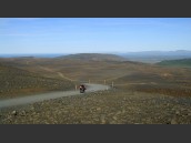 Motorcykel (MC) kör på grusväg i stenigt och kargt landskap på Island.