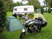 Två MC, Kawasaki Versys 650 och ER samt två uppslagna tält på grön och lummig camping i Tyskland.