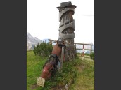 Konstverk av gammal rostig motorcykel och trädstam med skylt för Hotel Perla i Dolomiterna, Alperna.