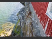 Klippa, tillika husgrund och röd vägg som skulpterats och slitits av havet och vinden.