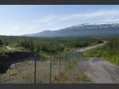 Väg E10 med en bil samt vy  mot Stordalen, Nordland, Norge på sommaren. Berg med lite snö samt blå himmel och lite slöjmoln i bakgrunden.