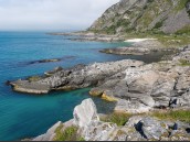 Kust med klart turkost vatten, klippor, vikar, grönska och sand på Andøya (Andöya), Vesterålen, Nordnorge, Norge.